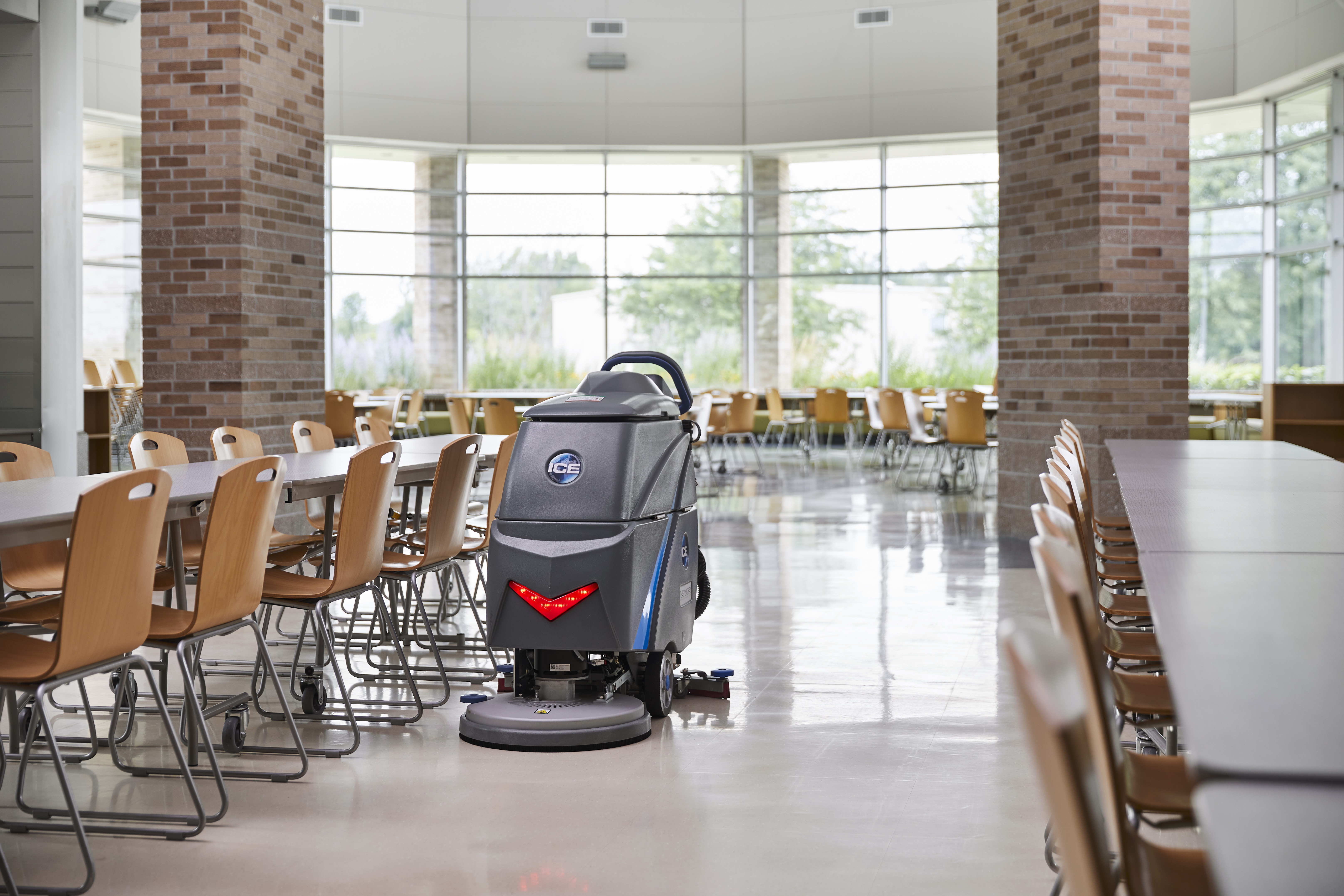 walk-behind floor scrubber placed inside a very clean school cafeteria