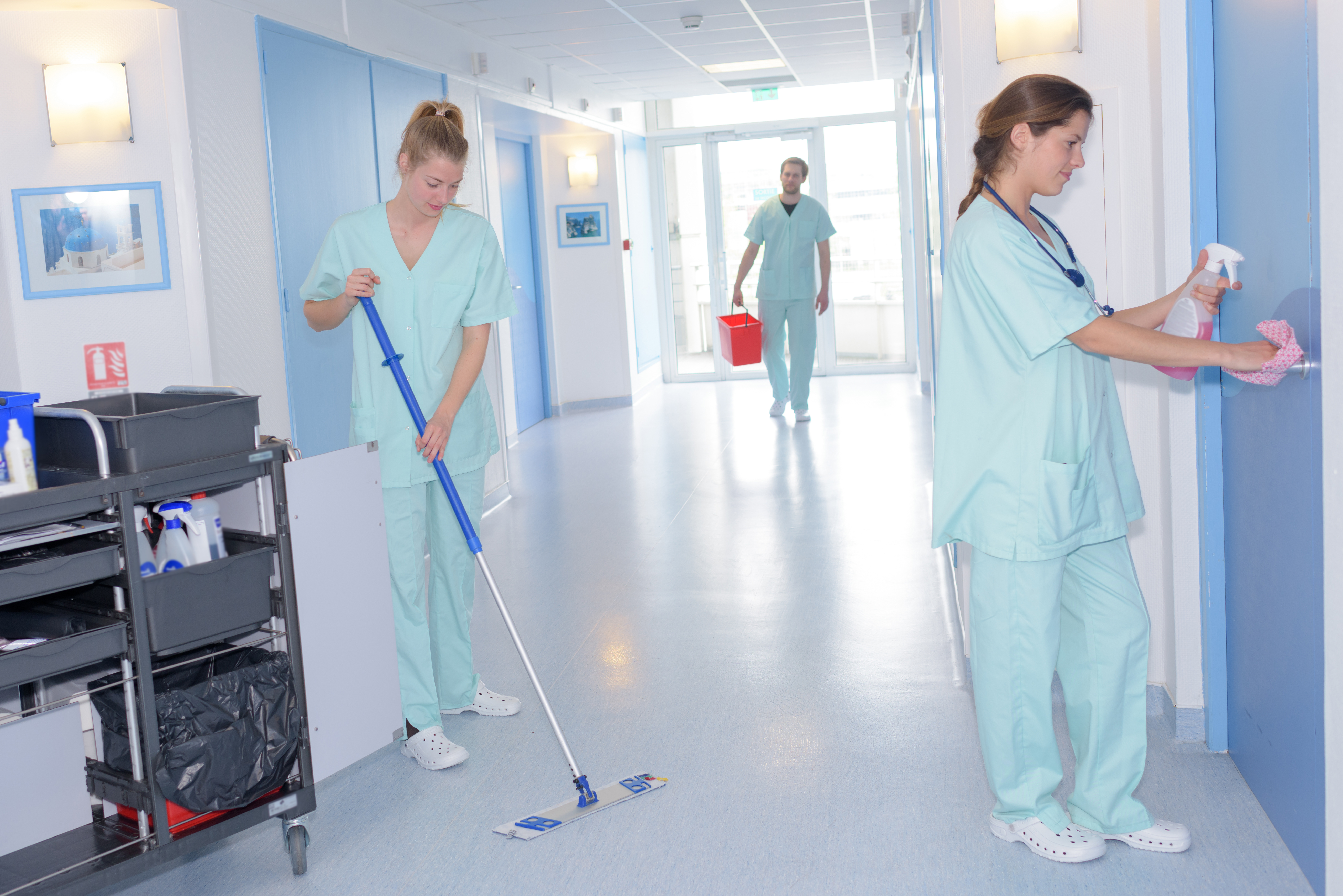 person in cleaning clothes mopping a healthcare facility