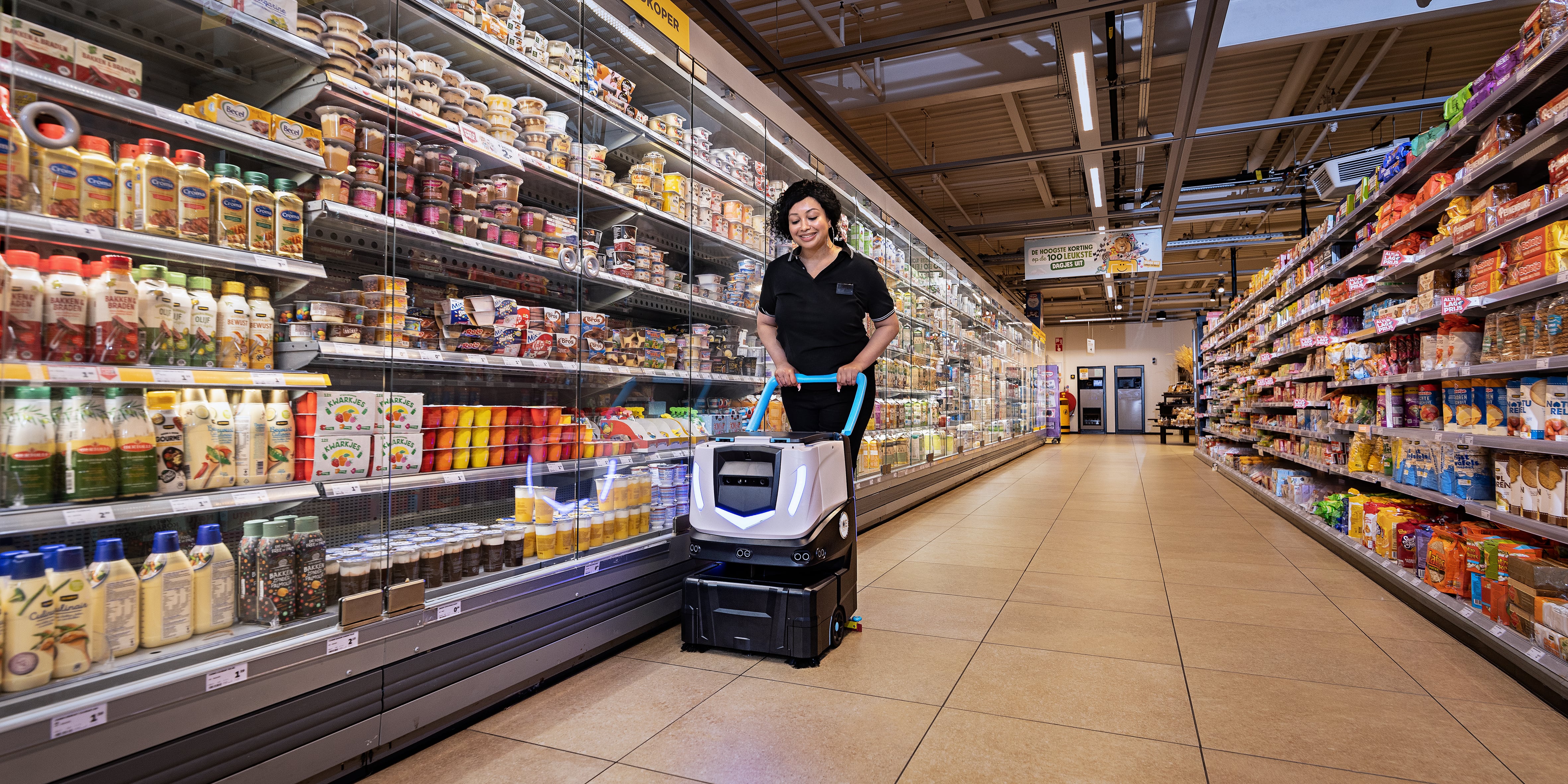 grocery store employee working with autonomous cleaning equipment 