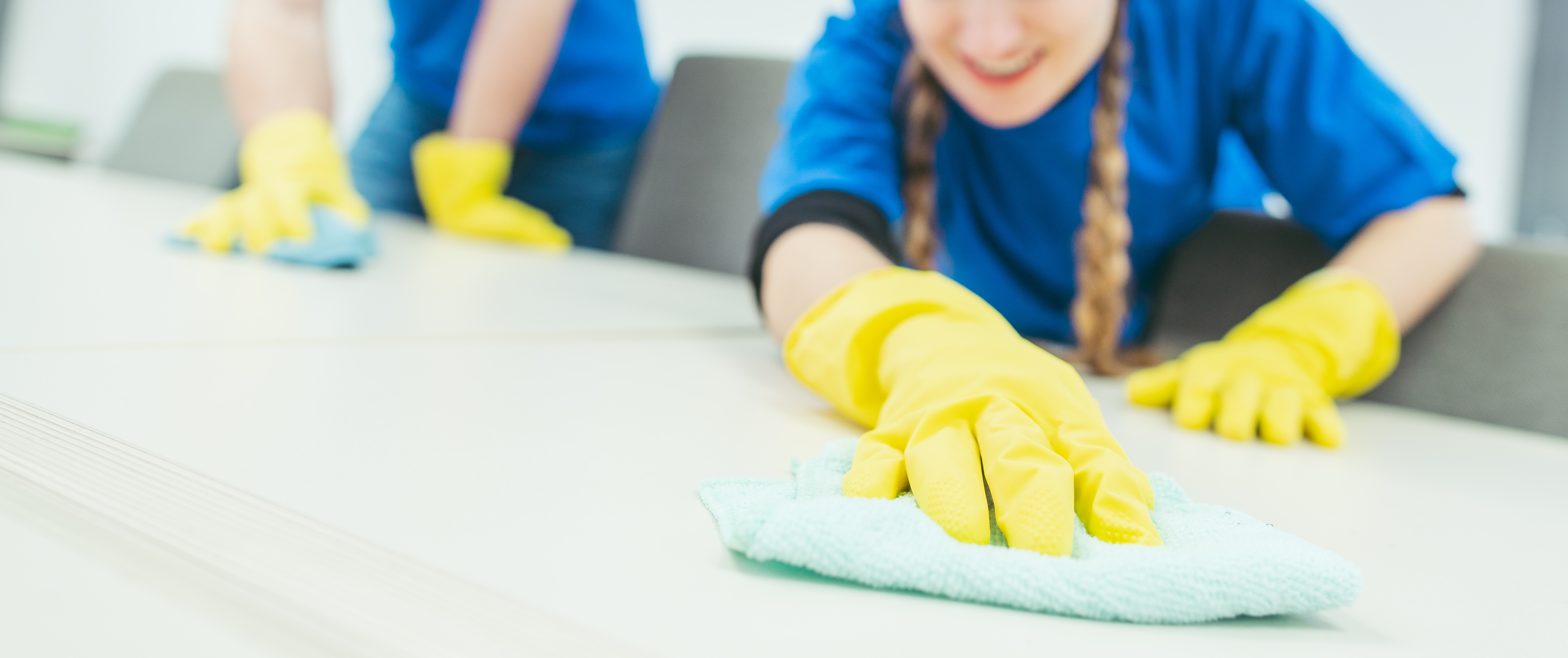 cleaning team members wearing yellow rubber gloves scrubbing a surface