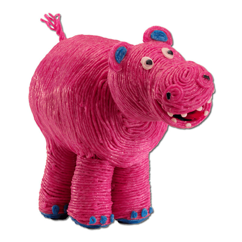 A pink hippo created from Wikki Sticks. The wax sticks are wound around and stuck to each other to create the body. The feet, and ear accents are blue and eyes and teeth are white. There is a frayed looking tail sticking up in the back. The hippo is large and rounded and appears to be smiling.