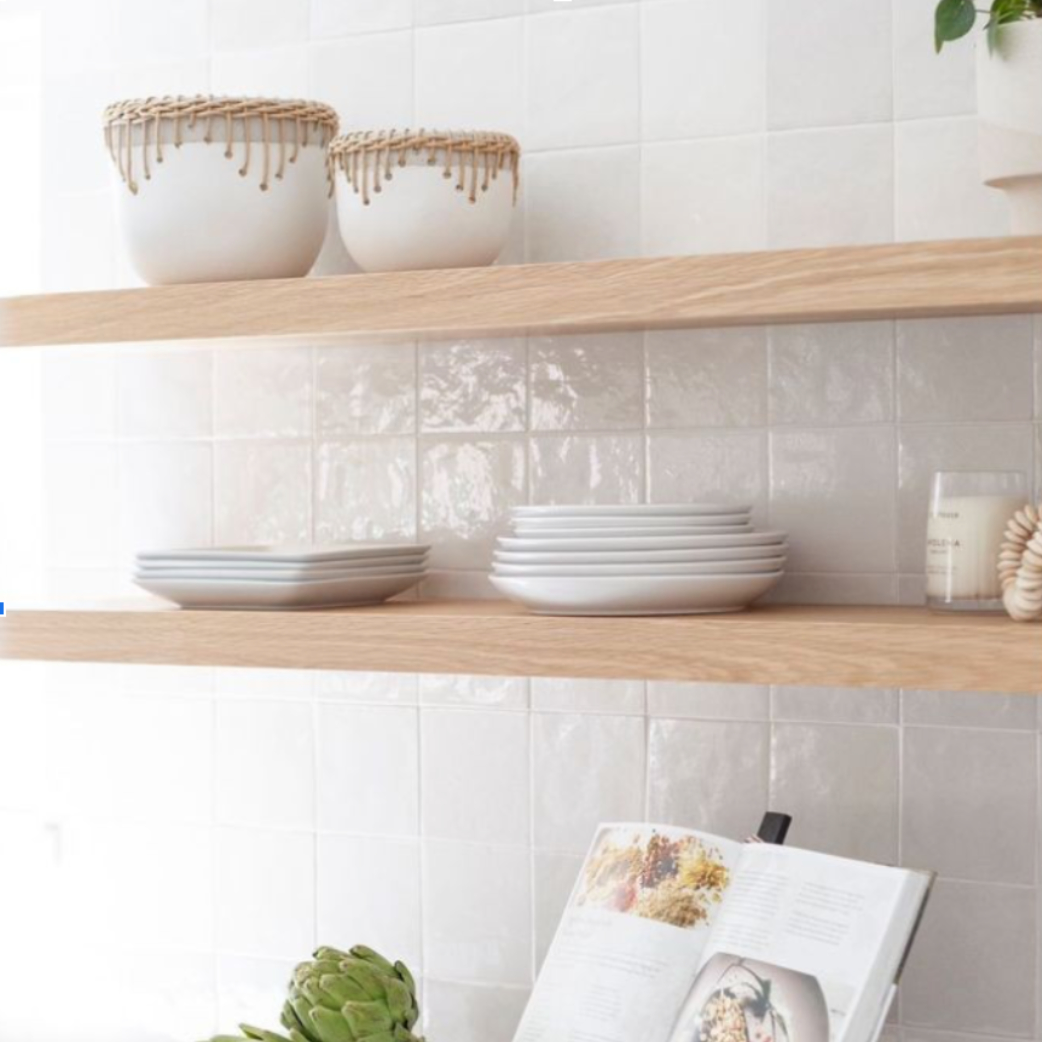 Two light stained wood floating shelves hung on a white, tile kitchen wall above the counter