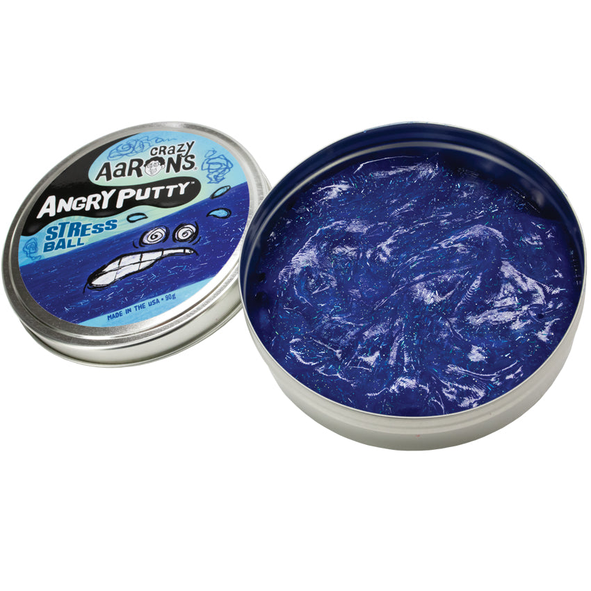 Crazy Aaron’s Angry Putty, Stress Ball. The large round tin has glittery dark blue putty swirled inside. The putty is reflecting the light and you can see the small, rectangular and circle shaped glitter inside the putty, shining in silver. The lid to the left shows a drawn stressed face with sweat beads splashing from the face on top of a band of putty. 