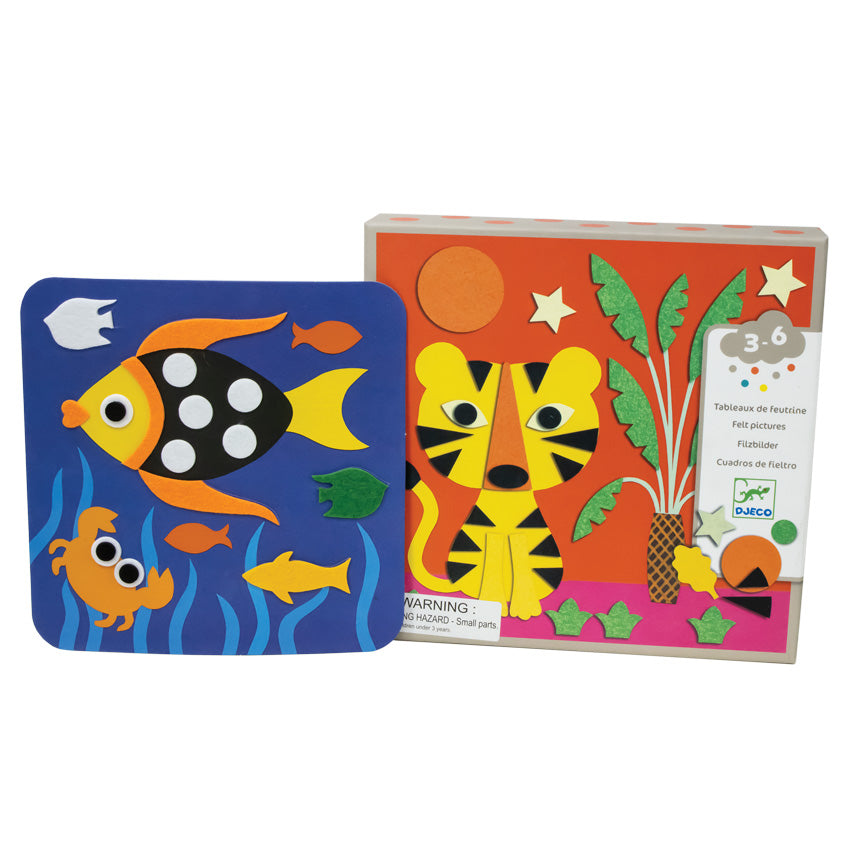 The Djeco Sweet Nature Felt set product box with a project. The box, to the right, is square-shaped and mainly red with a gray border. Over the red is tiger, a tree, a sun, stars, and bush sprouts. The project that is leaned up against the box on the left is an underwater theme. There are fish, a crab, and some seaweed on the blue background. The pieces on the page are shaped felt stickers.