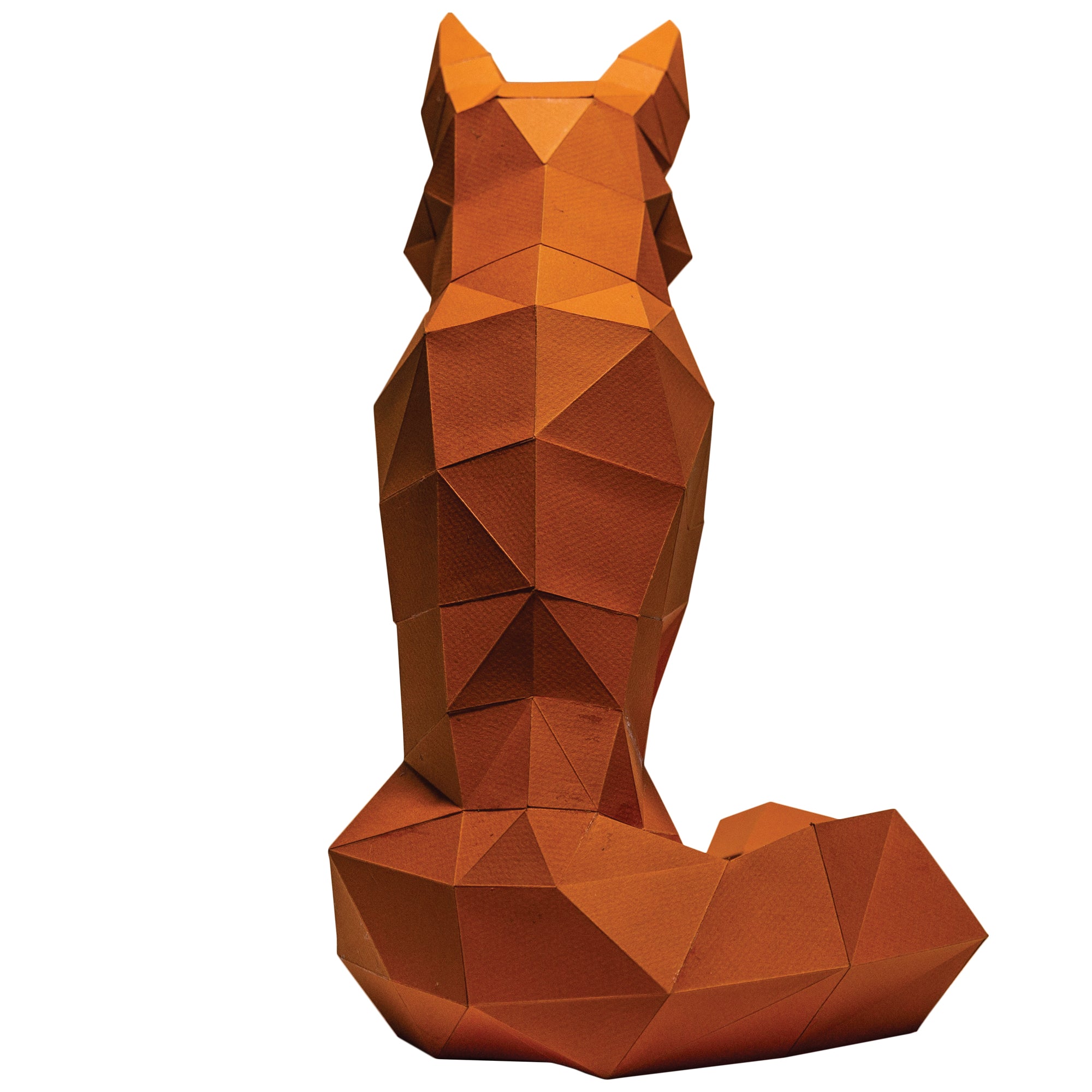 Back view of a Papercraft fox on a white background. Geometrical-shaped fox that is folded and cut paper pieces glued together. Fox is mainly a dark orange.