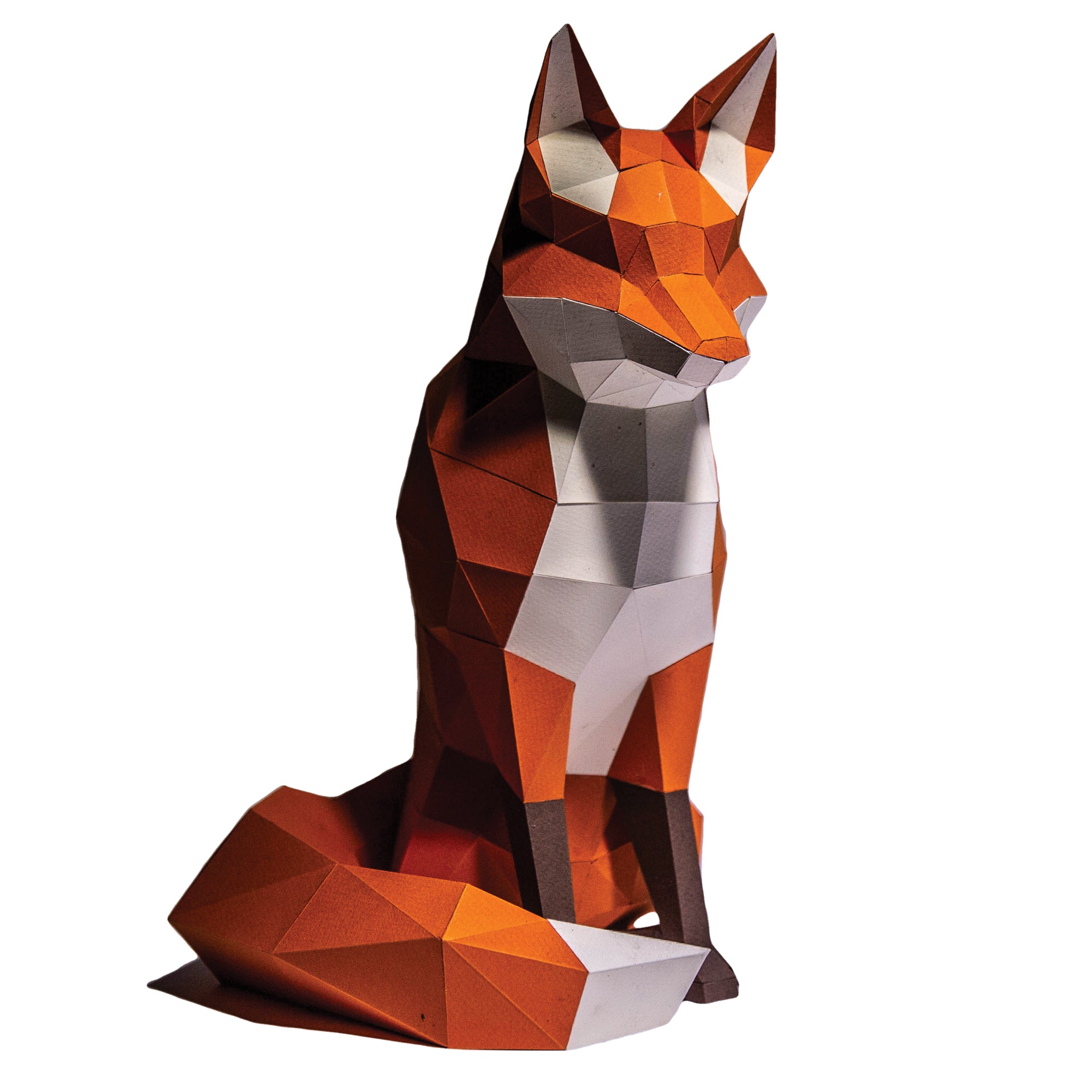 Papercraft fox on a white background. Geometrical-shaped fox that is folded and cut paper pieces glued together. Fox is mainly a dark orange with black paws and a white chest, chin area, inside ears, and tip of tail.
