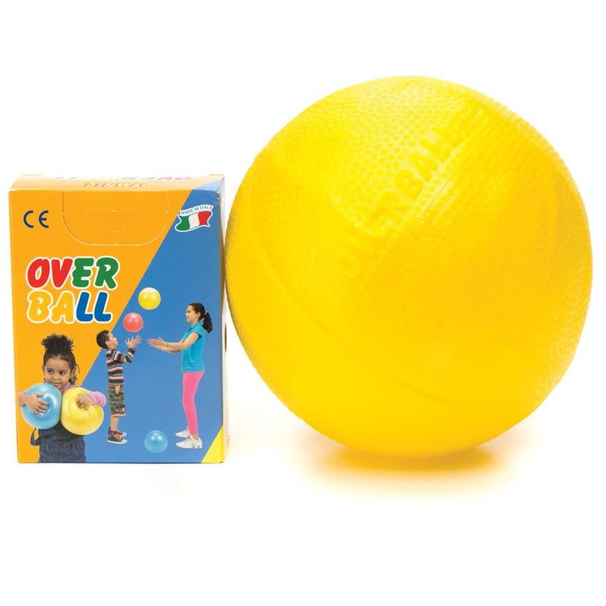 Yellow Gymnic Over Ball blown up and sitting next to its' packaging on the left. The ball has slight bumpy texture. The packaging is orange and blue with a colorful title and images f 3 children. One small dark-haired girl is holding 2 over balls in yellow and blue in the lower-left corner. To the right you see a dark-haired boy throwing a red ball up in the air and an older hark-haired girl throwing a yellow ball.
