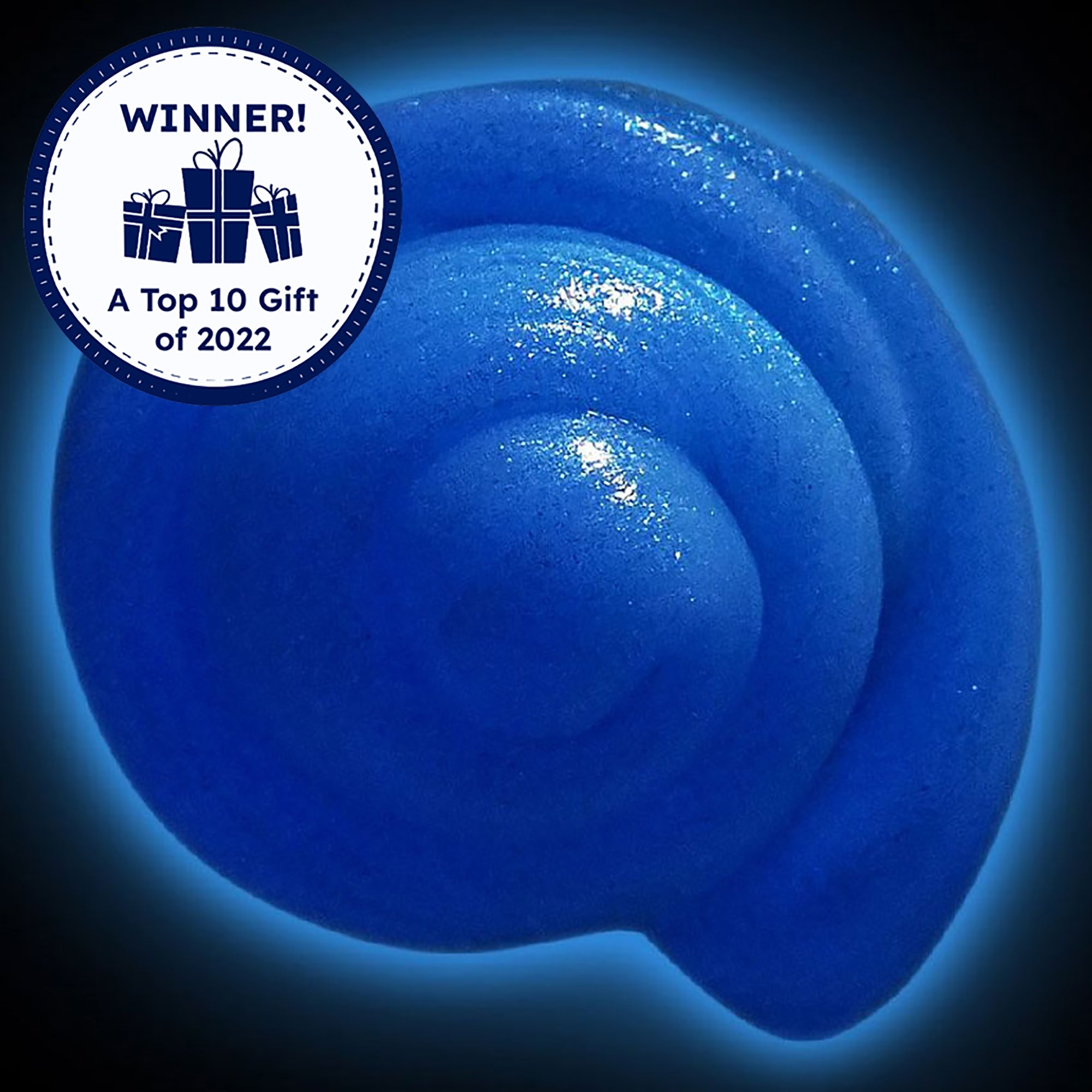 Mixed by Me, Glow, Thinking Putty. The shiny blue, glittered, putty is swirled like a snail shell. The background is black with a blue glow coming from the putty, showing that it is glowing in the dark. There is a Timberdoodle, Top 10 Gift of 2022, award seal is placed over the top-left of the picture.