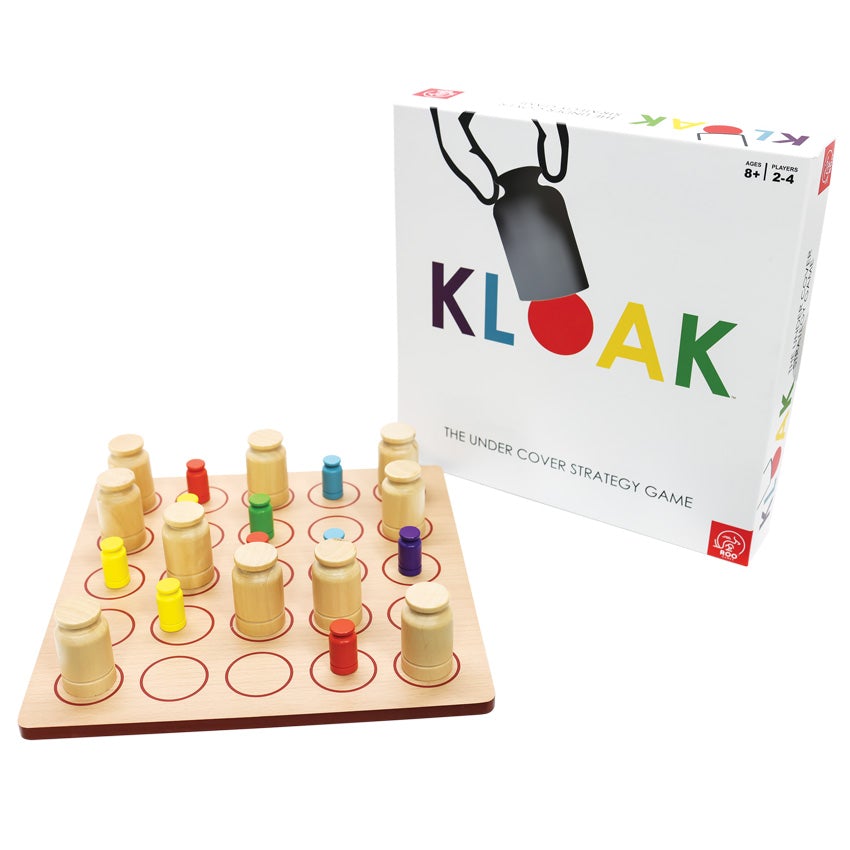 Kloak game with the box to the right. The box cover is white with each letter of the title a different color. There is a cut-out above the O in Kloak in the shape of the game cover piece with an illustrated hand grabbing the cover piece. The game, on the left, is a wooden square board with rounded corners and a grid of 5 by 5 circles on top. The pieces on top are colored wooden pieces that are rectangular with a tip shaped like a knob. The cover pieces are the same shape, but larger, and are wood colored.