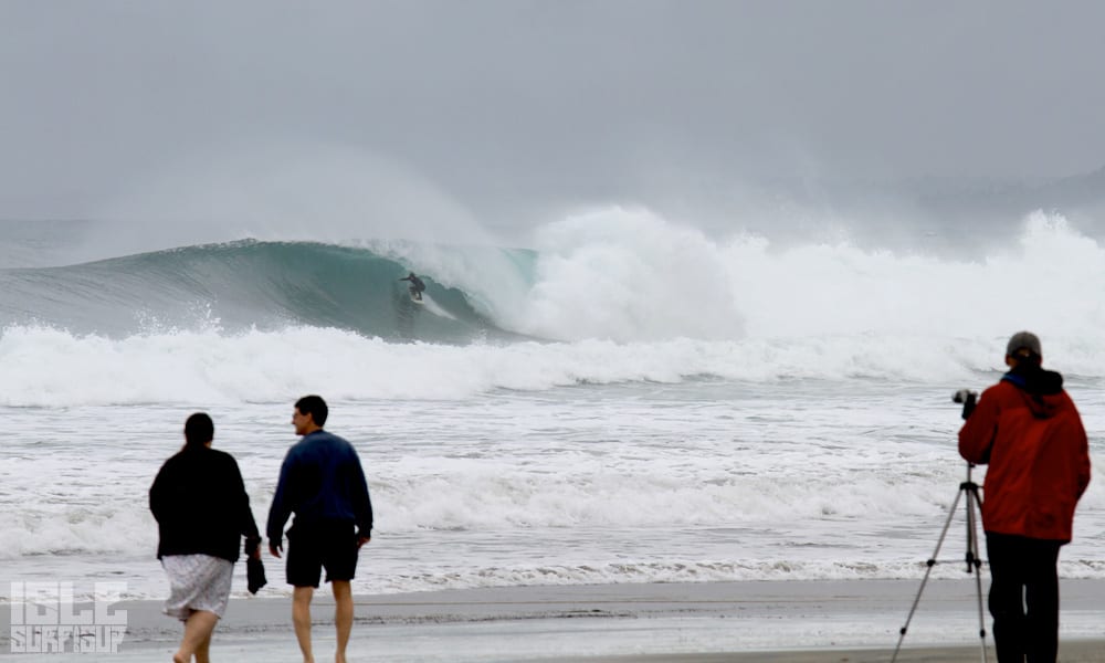 beach goers look on as a surfer get barreled in the huge surf la jolla