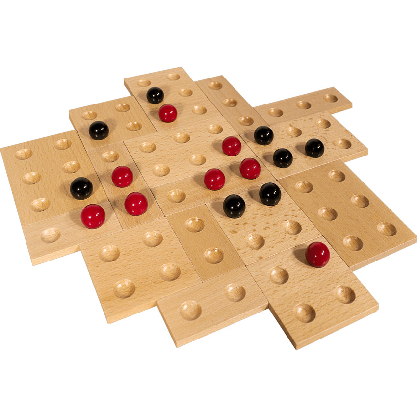 Kulami game in play. There are many square and rectangle wood pieces with divots to place black and red marbles. The wood pieces are placed randomly against each other for form a gapless board. The 8 red and 8 black marbles are randomly placed on top.