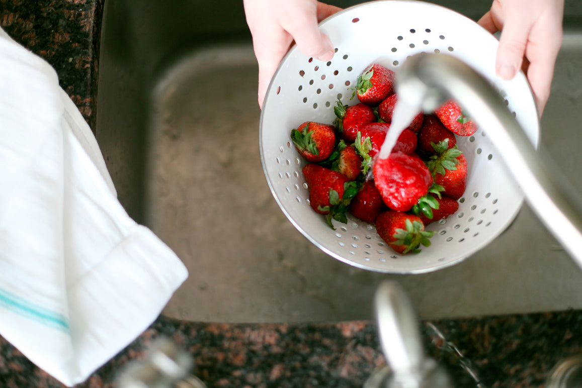 Personne lavant un bol de fraise avec le nettoyant pour fruits et légumes d'ATTITUDE
