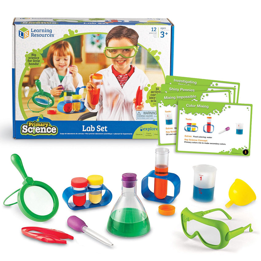 Primary Science Lab Kit contents. Top right is the Lab Kit box. To the right are the set of activity cards. Below shows a magnifying glass, tweezers, baster, 2 short test tubes in a stand, eyedropper, tall test tube in a stand, measuring cup, funnel, and safety goggles.