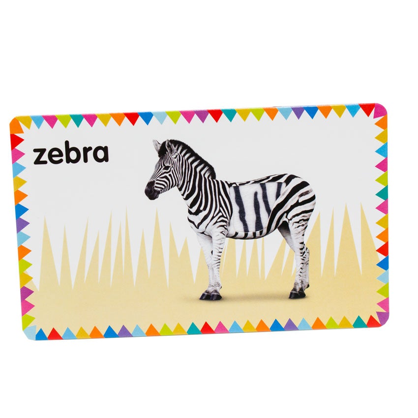 My First Touch and Feel Cards: First Words card showing a standing zebra with the word "zebra" written in the top-left corner. There is a spot on the zebra that provides a realistic fur texture. The background is white with tall brown grass and has a colored triangle-shaped flags all around the border.