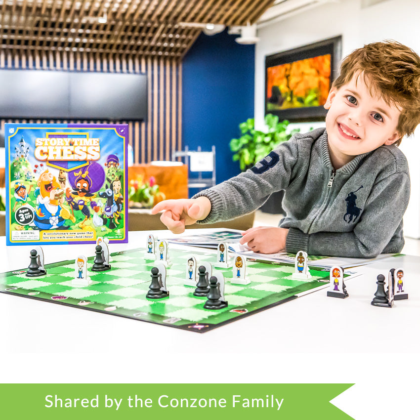 A customer photo of a dark-blonde boy staring at the camera and pointing to the game board on the table in front of him and leaning his other arm on the instruction and story manual. The game board squares are green grass, alternating darker green and lighter green. The pieces are standard chess shape, but has a character cut-out attached to each piece. The game box can be seen clearly on the left of the table.