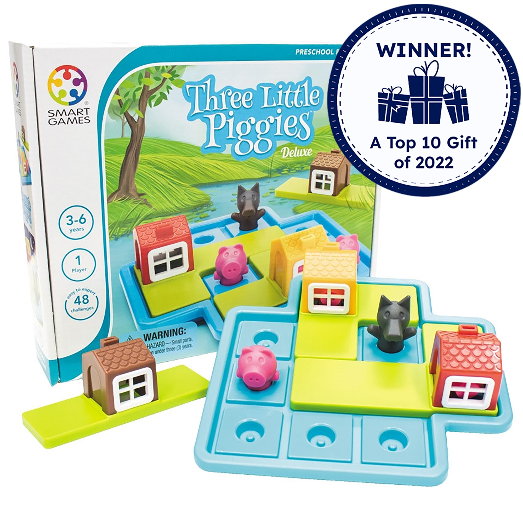 Three Little Piggies game box with the game setup in front of it. The game board is light blue with squares to put the playing pieces on. There are playing pieces on the board, including; a red house, a yellow house, 3 pigs, and a wolf. Off to the left side is a brown house piece. There is a badge reading “Winner! A top 10 gift of 2022” in the top-right of the picture.
